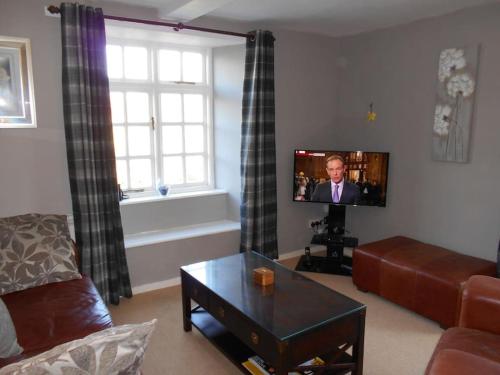a living room with a couch and a flat screen tv at The Granary, Old Corn Mill, Yorkshire Dales in West Burton