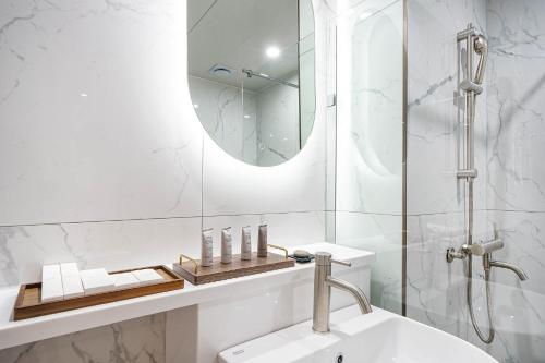 a white bathroom with a sink and a mirror at Browndot Hotel Jeonju Ajung in Jeonju