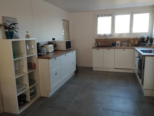 uma cozinha com armários brancos e piso em azulejo em Appartement cosy proche mer em La Seyne-sur-Mer