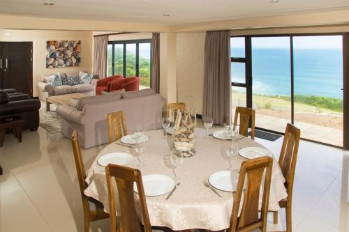 uma sala de jantar com uma mesa com copos de vinho em Dolphins on Six Self Catering Apartments em Wilderness