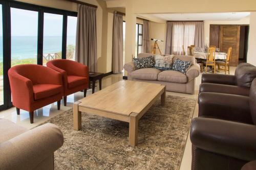 uma sala de estar com sofás e cadeiras e uma mesa em Dolphins on Six Self Catering Apartments em Wilderness