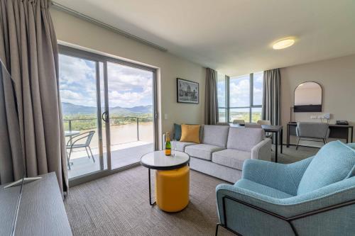 a living room with a couch and chairs and a balcony at Quest Rockhampton in Rockhampton