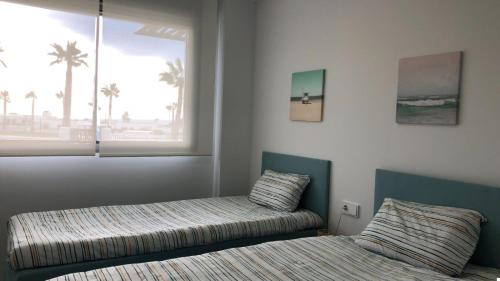a bedroom with two beds and a window with palm trees at Apartment Seascape Relax in Finestrat