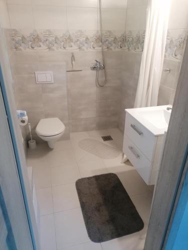 a white bathroom with a toilet and a sink at Apartament z tarasem in Bodzentyn