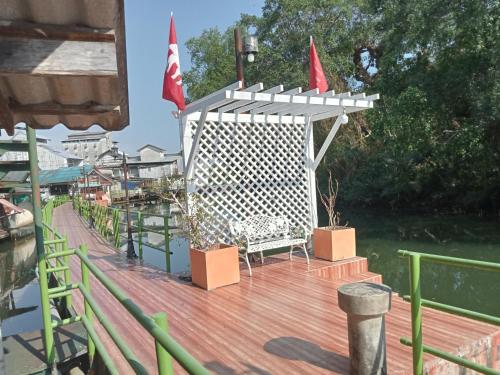 a deck with a bench and flags on the water at NP guesthouse in Trat