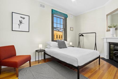 a bedroom with a bed and a chair and a fireplace at Discover The Rocks - Historical Terrace House in Sydney
