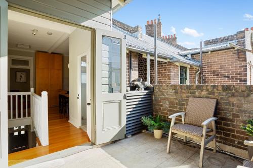 a patio with a door and a chair on a brick wall at Discover The Rocks - Historical Terrace House in Sydney