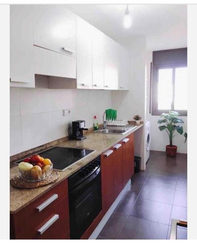 eine Küche mit weißen Schränken und einer Obstschale auf der Theke in der Unterkunft Apartamento en el Corazon del Delta in Sant Jaume d’Enveja