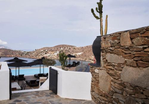 a stone wall next to a patio with a pool at Liostasi in Ios Chora