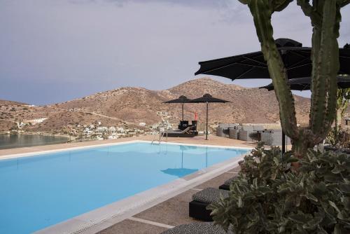 a swimming pool with umbrellas and a mountain in the background at Liostasi in Ios Chora