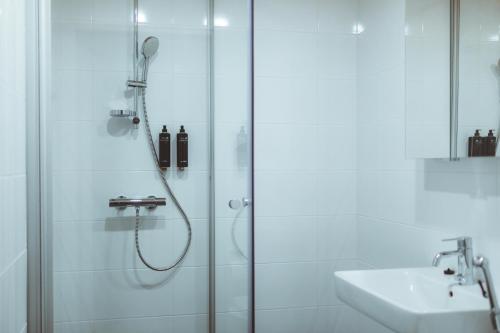a shower with a glass door next to a sink at Apukka Rovaniemi City Apartments in Rovaniemi