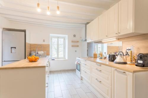 une cuisine avec des armoires blanches et un comptoir dans l'établissement Maison Valeli - Maison de charme à 1h de Paris, à Lavilletertre