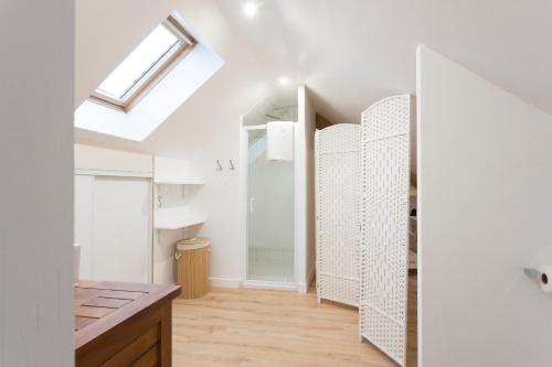 a bathroom with white walls and a skylight at Maison Valeli - Maison de charme à 1h de Paris in Lavilletertre