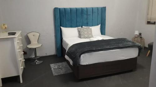 a bedroom with a bed with a blue headboard at City Dons Guest House in Vereeniging