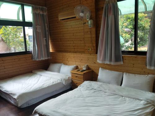 two beds in a room with two windows at Meiting B&B in Shuili