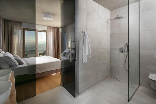a bathroom with a shower and a bed and a glass shower stall at Green Tree Villas in Rabac