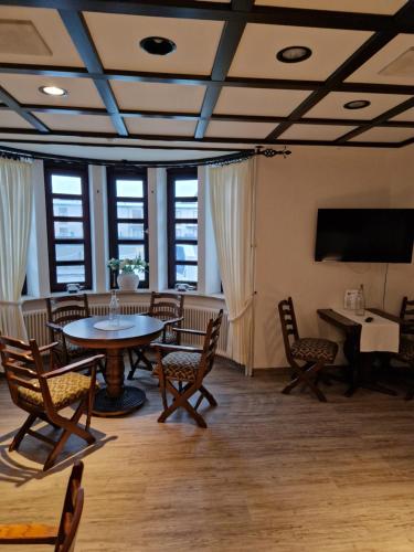 ein Zimmer mit Tisch und Stühlen und einem Fernseher in der Unterkunft Hotel Meeresfriede in Cuxhaven