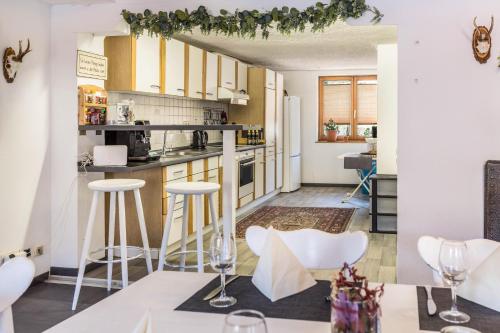 a kitchen with white cabinets and bar stools at Haus Steinatal in Ühlingen-Birkendorf
