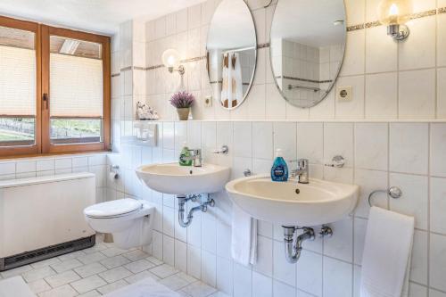 a bathroom with two sinks and a toilet and a mirror at Haus Steinatal in Ühlingen-Birkendorf