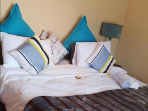 a bedroom with a bed with blue and white pillows at Edwaleni Guest Lodge in Pinetown