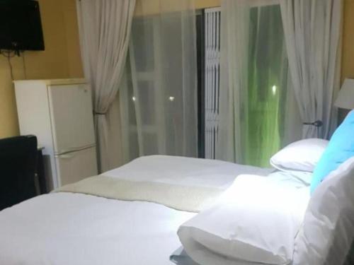 a bedroom with two white beds and a window at Edwaleni Guest Lodge in Pinetown