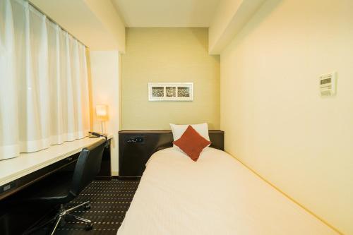 Habitación pequeña con cama y escritorio. en Kanda Station Hotel, en Tokio