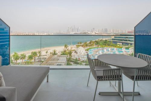 杜拜的住宿－W Dubai - The Palm，阳台配有桌椅,享有海滩美景。