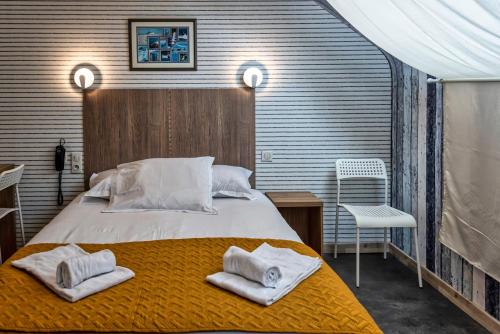 a bedroom with a large bed with towels on it at Hotel La Voilerie Cancale bord de mer in Cancale