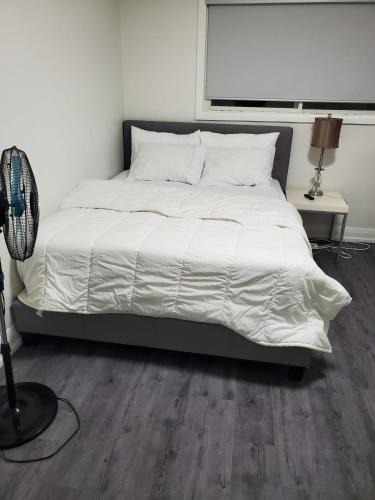 een bed met een wit dekbed in een slaapkamer bij Maxwell Esabu in Toronto