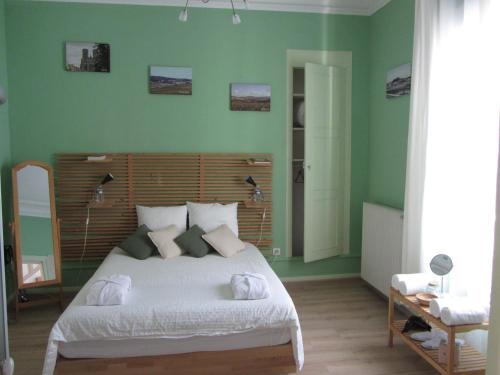 a bedroom with a large white bed with green walls at Chambre D'hôtes Les Epicuriens in Épernay