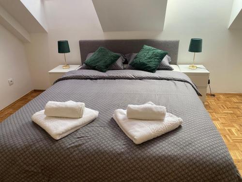 Una cama grande con dos toallas blancas. en Vlasic Apartmani CENTAR, en Vršac