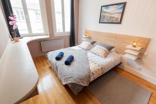 um quarto com uma cama com chinelos azuis em Joli T2 tout équipé Quartier Piéton par Groom* em Lorient