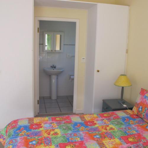a bedroom with a bed and a bathroom with a sink at Constantia Cottage in Cape Town