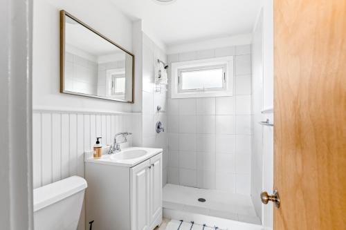 a white bathroom with a sink and a mirror at Don't Ditch Your Plains in Montauk