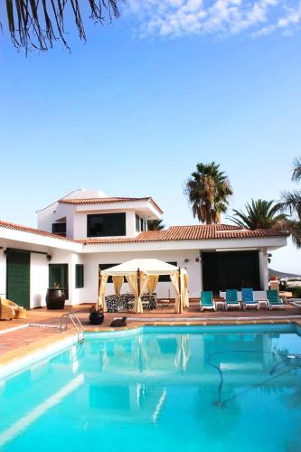 a villa with a swimming pool in front of a house at Los Fondos in Costa Del Silencio