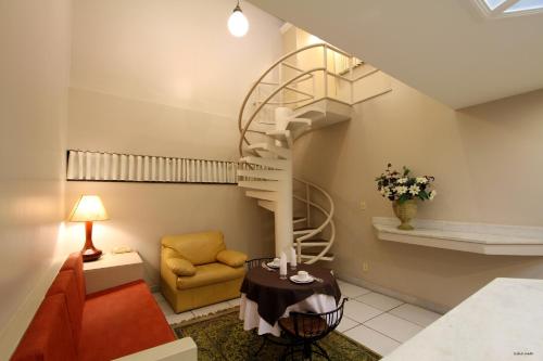 a living room with a spiral staircase and a chair at Vicenza Apart Hotel in São João del Rei
