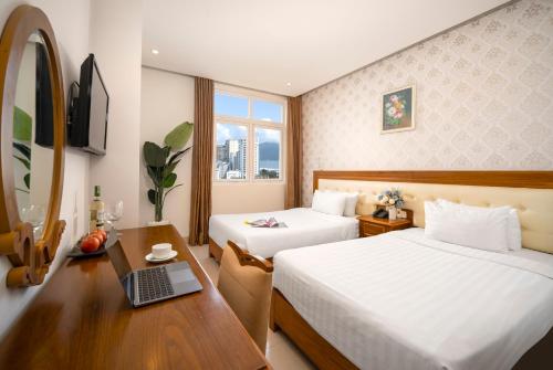 a hotel room with two beds and a desk with a laptop at Royal Family Hotel in Da Nang