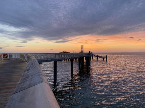 a pier on the water with a sunset in the background at Hotel & Restaurant Hanse Kogge in Ostseebad Koserow