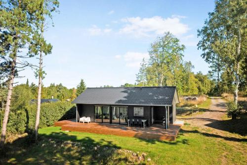 a house with a black roof and a wooden deck at New Summer House From 2021 With Sea View in Millinge