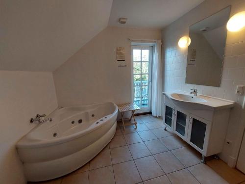 Baño blanco con bañera y lavamanos en Beautiful Holiday Home With Spa And Sauna Close To Nature, en Gjern