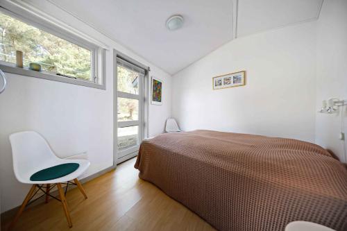 a bedroom with a bed and a chair and a window at Holiday Apartment In Dueodde Holiday Park in Neksø