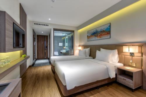 a bedroom with a large white bed and a bathroom at Maris Hotel Nha Trang in Nha Trang