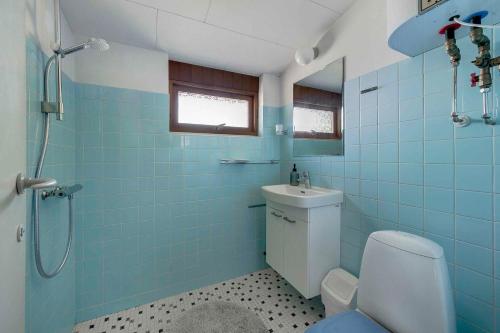 W wyłożonej niebieskimi kafelkami łazience znajduje się toaleta i umywalka. w obiekcie Awesome Home In Hirtshals With 3 Bedrooms And Wifi w mieście Hirtshals