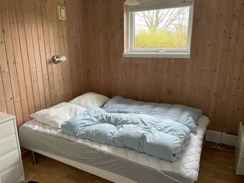ein unmaskiertes Bett in einem Zimmer mit Fenster in der Unterkunft Holiday Home With Sauna And View To The Baltic Sea in Nordborg