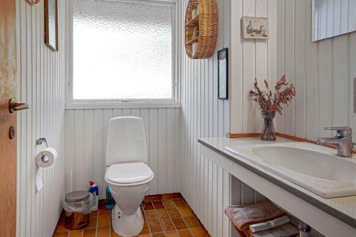uma casa de banho com um WC, um lavatório e uma janela em Lovely Cottage In Fredsskoven, Bjerge Strand, West Zealand em Store Fuglede