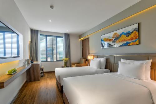 a hotel room with two beds and two windows at Maris Hotel Nha Trang in Nha Trang