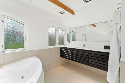 uma casa de banho com uma banheira, um lavatório e 2 janelas em Holiday Home With Pool And Panoramic View Of The Sea em Asperup