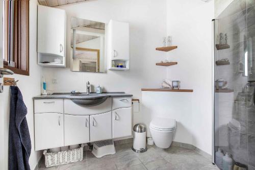ein weißes Bad mit einem Waschbecken und einem WC in der Unterkunft Bright, Spacious And Cozy Cottage, 200 M From The Beach in Hadsund