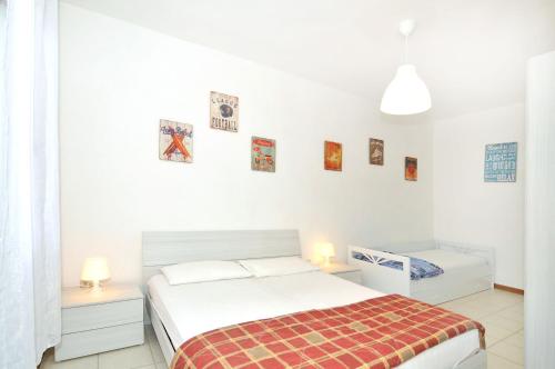a white bedroom with a bed and two night stands at Casette Baradel - Agenzia Caorle in Caorle