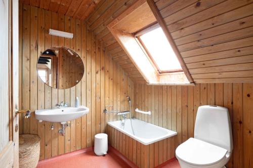een badkamer met een wastafel, een bad en een toilet bij Wooden House With A View Of The North Sea in Lemvig